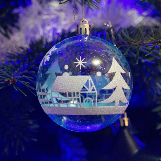 En julekugle lavet af glas der hænger på et grantræ 