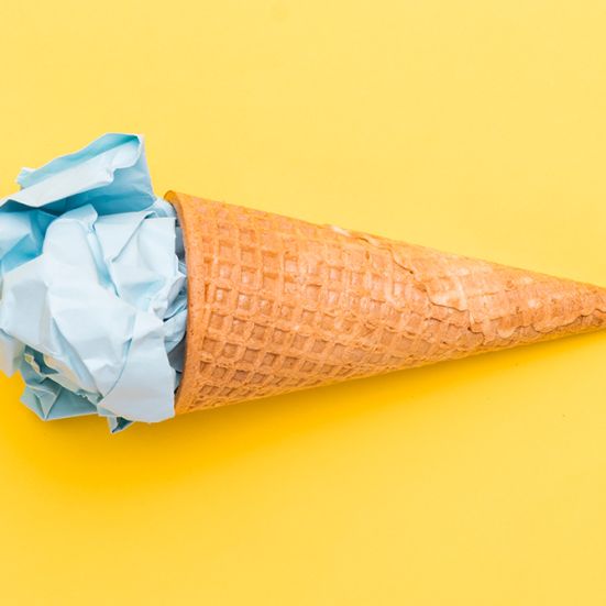 Isvaffel med blå papirkugle i toppen på gul baggrund