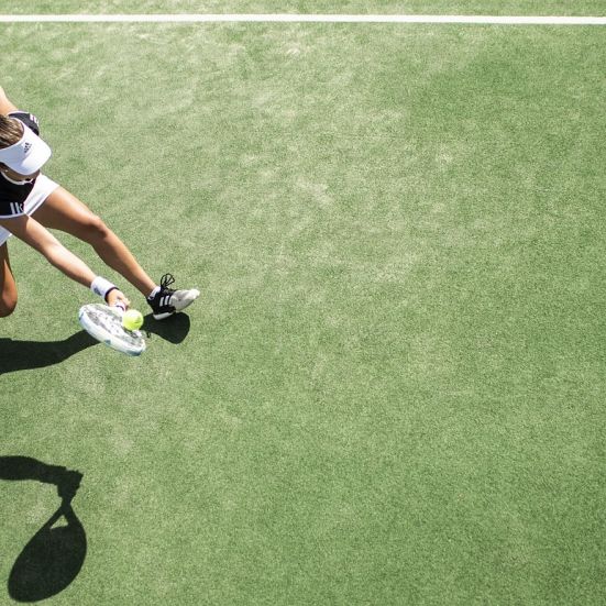 En kvinde der slår til en tennisbold set oppefra