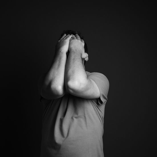 En mand der tager sig til hovedet i et mørkt rum 