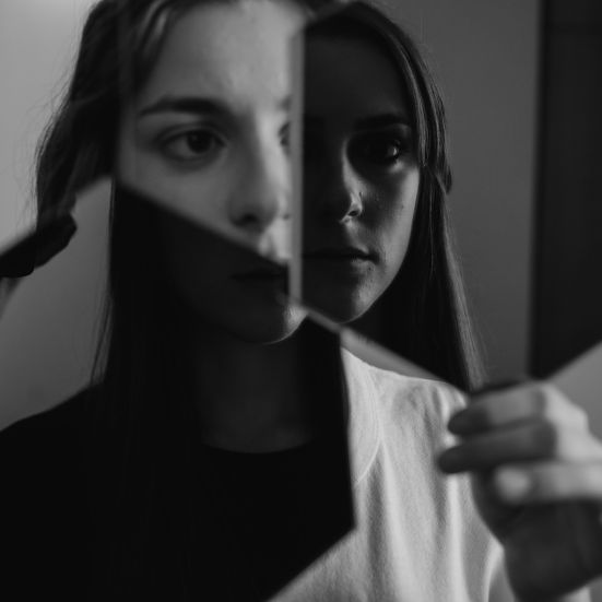 En kvinde der ser sig selv blive spejlet i to hexagoniske spejle