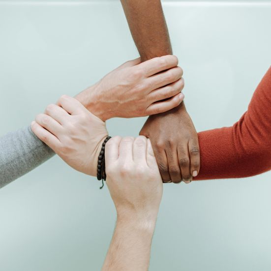 Fire hænder der holder om hinanden i en cirkel 