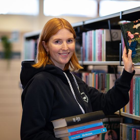 Bibliotekets litteraturformidler Mette tager en bog fra hylden