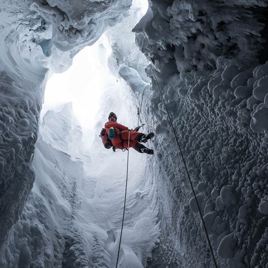 Mand firer sig ned med reb i en isgrotte