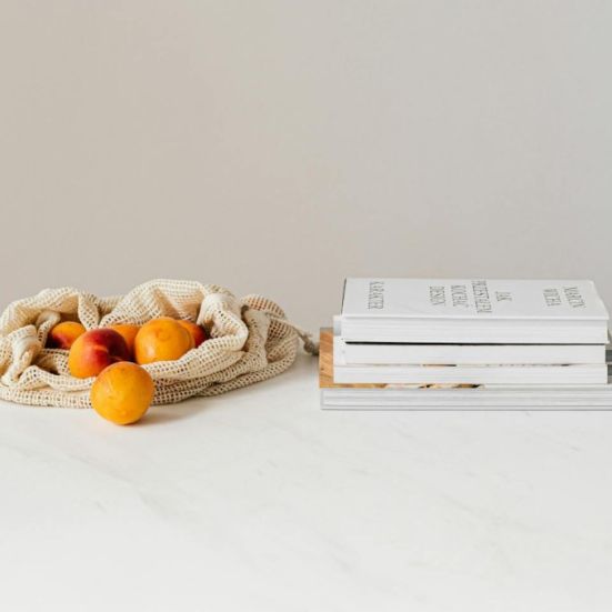 En pose lime der er vedsiden af en stak bøger på et marmorbord