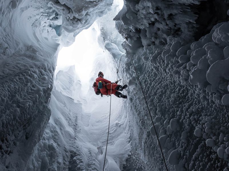 Mand firer sig ned med reb i en isgrotte