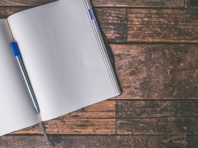 En notesblok med en kuglepen liggende på et træbord