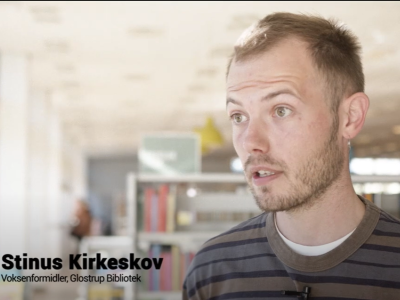 Et billede af voksenformidler Stinus Kirkeskov med biblioteket i baggrunden