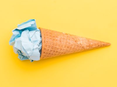 Isvaffel med blå papirkugle i toppen på gul baggrund