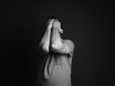 En mand der tager sig til hovedet i et mørkt rum 