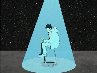En ung dreng der sidder på en stol i et mørkt rum med en lyskegle over sig og en telefon i hånden