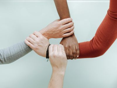 Fire hænder der holder om hinanden i en cirkel 