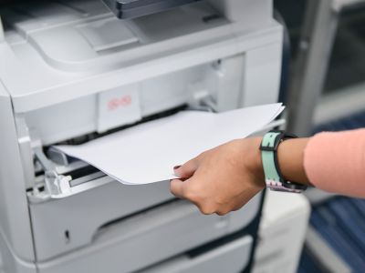 Hånd tager papir ud af printer