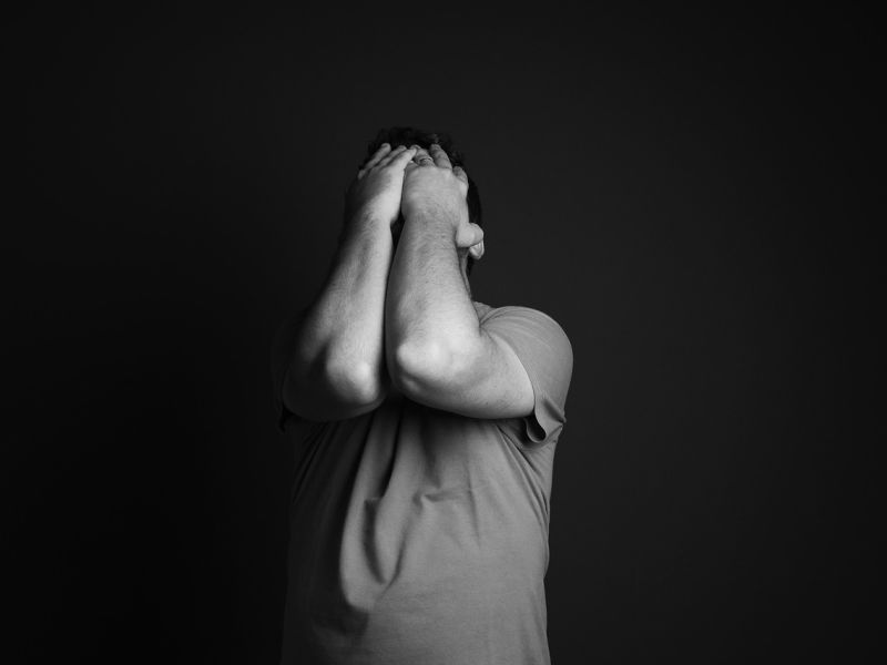 En mand der tager sig til hovedet i et mørkt rum 