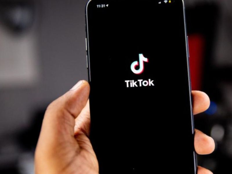 Hånd holder en smartphone med TikToks logo på skærmen.
