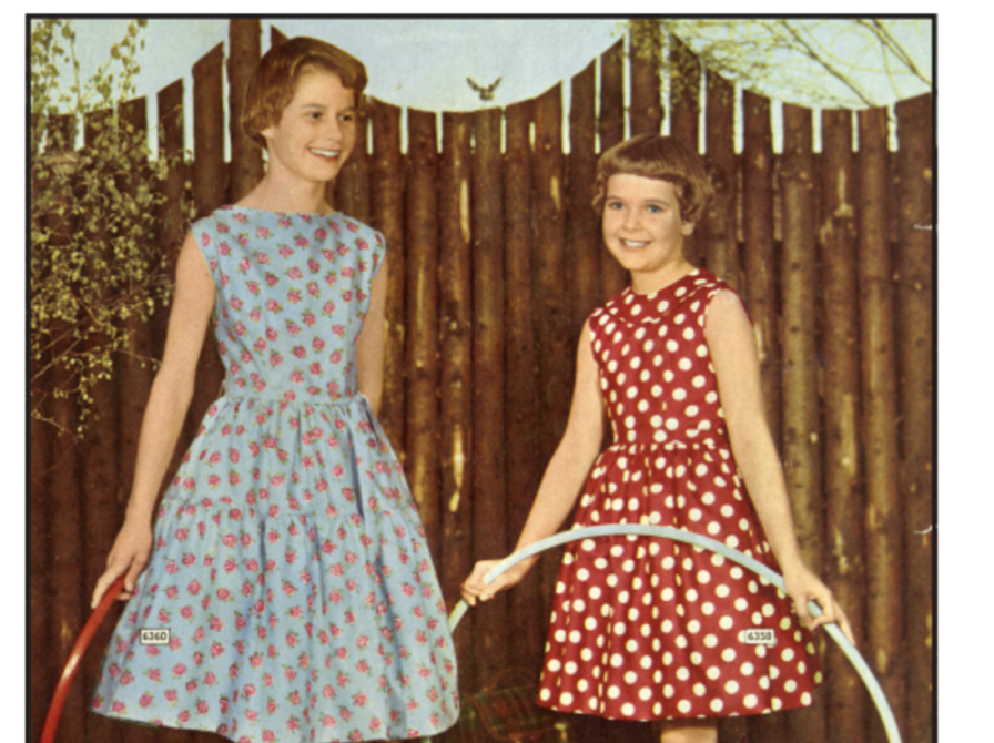 En kvinde og en pige der står med en hulahopring foran et træværk